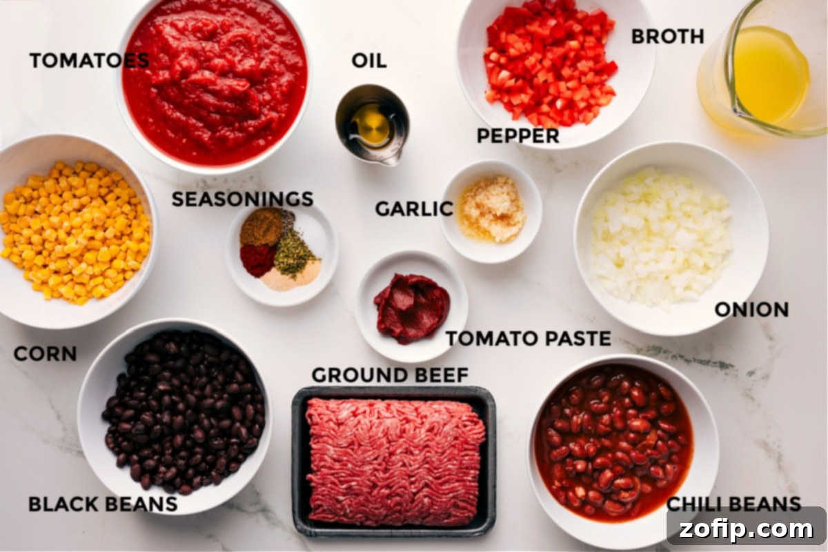 A vibrant selection of fresh ingredients laid out for the cornbread casserole recipe, including corn kernels, black beans, crushed tomatoes, a variety of seasonings, olive oil, lean ground beef, minced garlic, diced bell peppers, chopped onions, chili beans, and chicken broth.