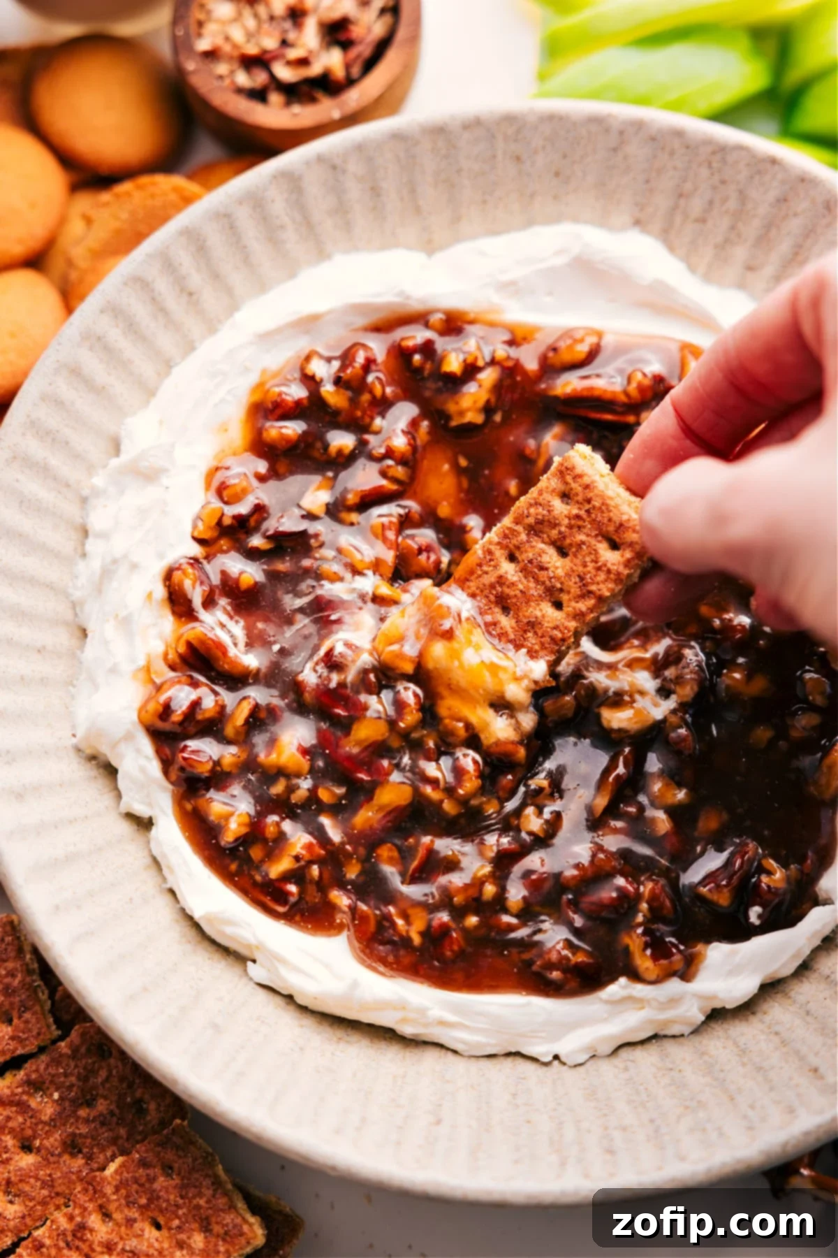A scoop of creamy fall pecan pie dip with a graham cracker being dipped in, showcasing its rich texture and tempting appeal.