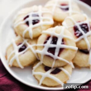 A plate of freshly baked Raspberry Thumbprint Cookies with a delicate glaze and jam filling.
