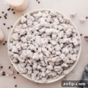 Popcorn Puppy Chow, a delightful mix of popcorn, chocolate, peanut butter, and powdered sugar, shown in a rustic serving bowl.