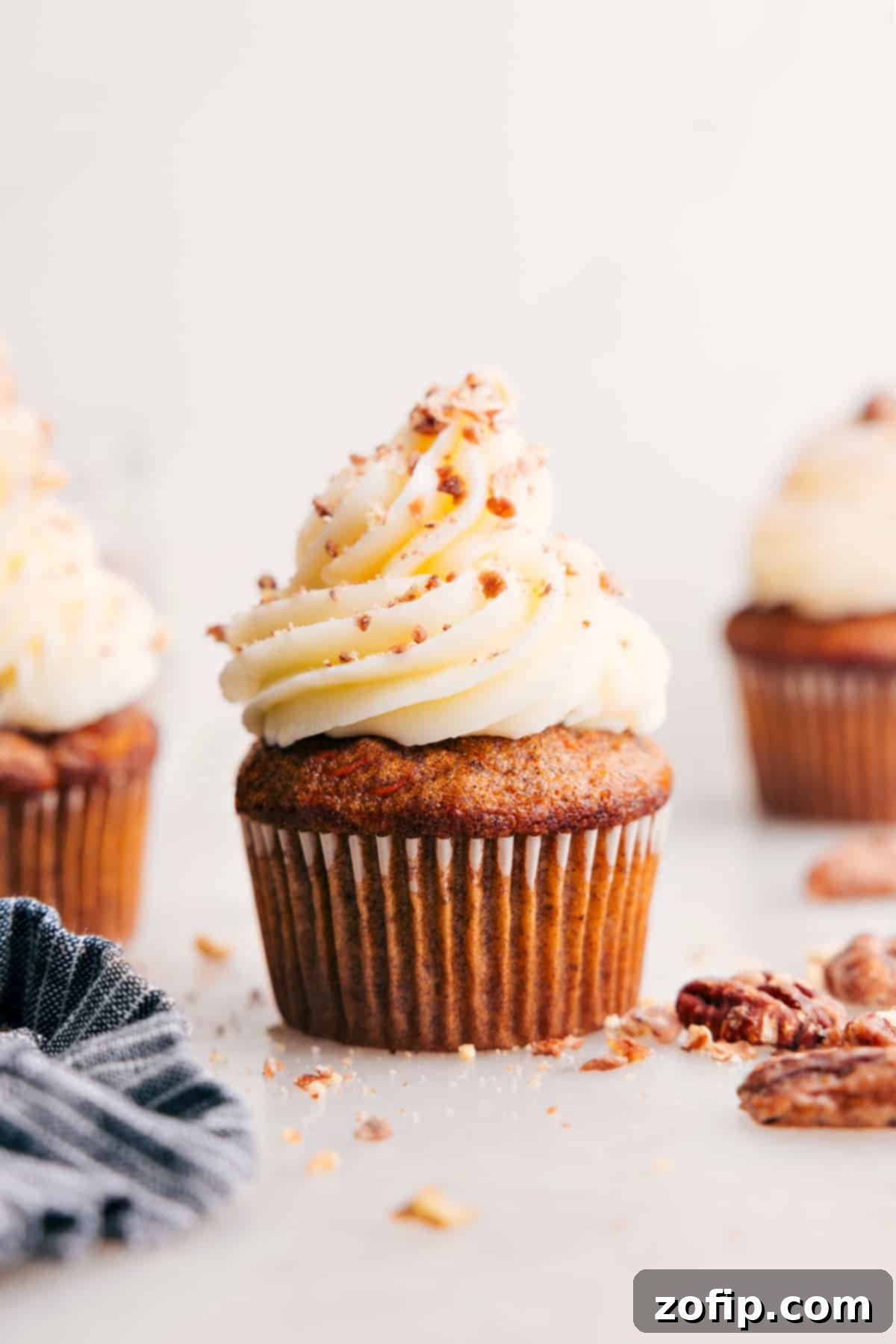 Delicious Carrot Cake Cupcakes generously topped with cream cheese frosting and pecans.
