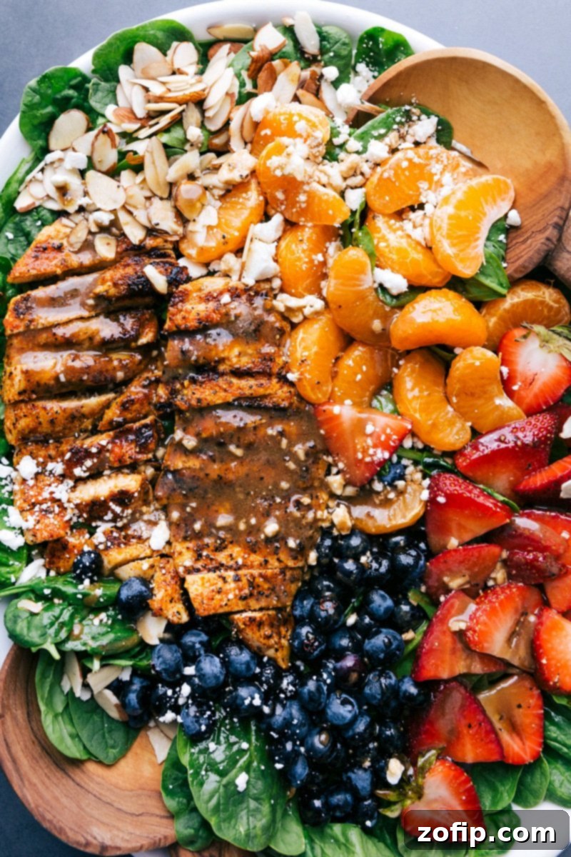 Deliciously Healthy Spinach Chicken Salad: Perfect Blend of Chicken, Spinach, Fruits, Dressing, and Nuts A completed Chicken Spinach Salad with neatly sliced chicken, fresh spinach, and a generous topping of fruit, dressing, and nuts, ready to be served.