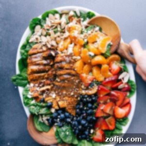 Wholesome Chicken Spinach Salad 2 Chicken spinach salad on a large platter, elegantly dressed and garnished with fresh fruit and nuts.