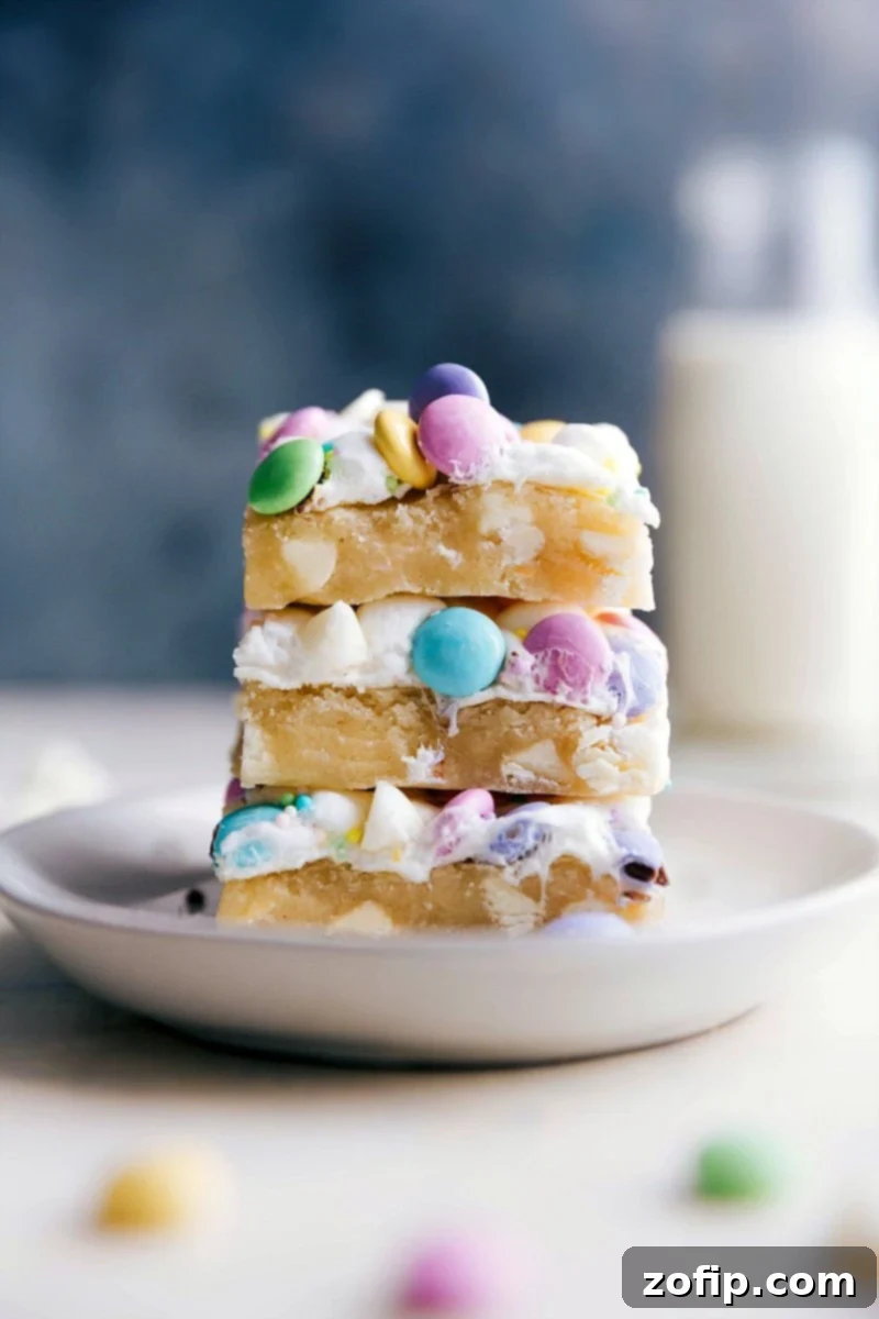 A stack of colorful Spring Confetti Bars, showing layers of cookie, marshmallow, M&M's, and sprinkles, ready for a spring celebration.