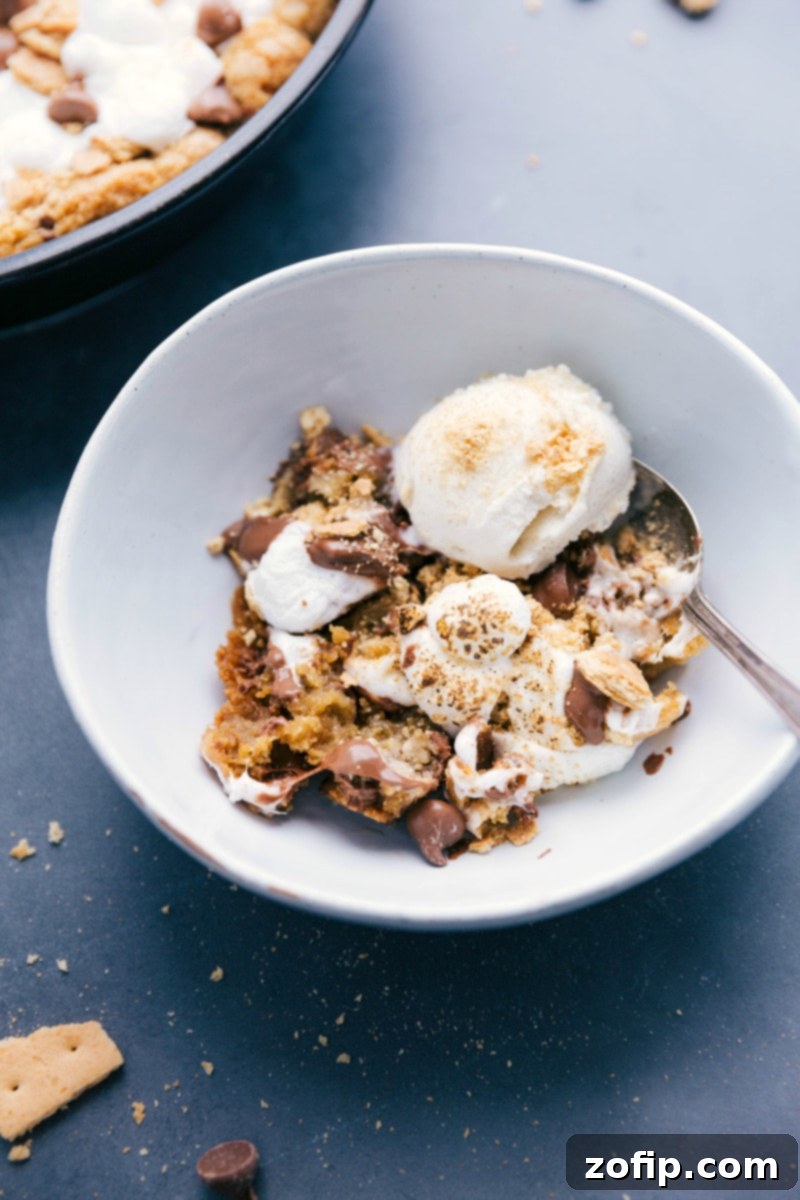 Warm S'mores Pizookie served in a bowl, generously topped with scoops of vanilla ice cream, creating a perfect blend of warm cookie and cold ice cream for a delightful dessert.