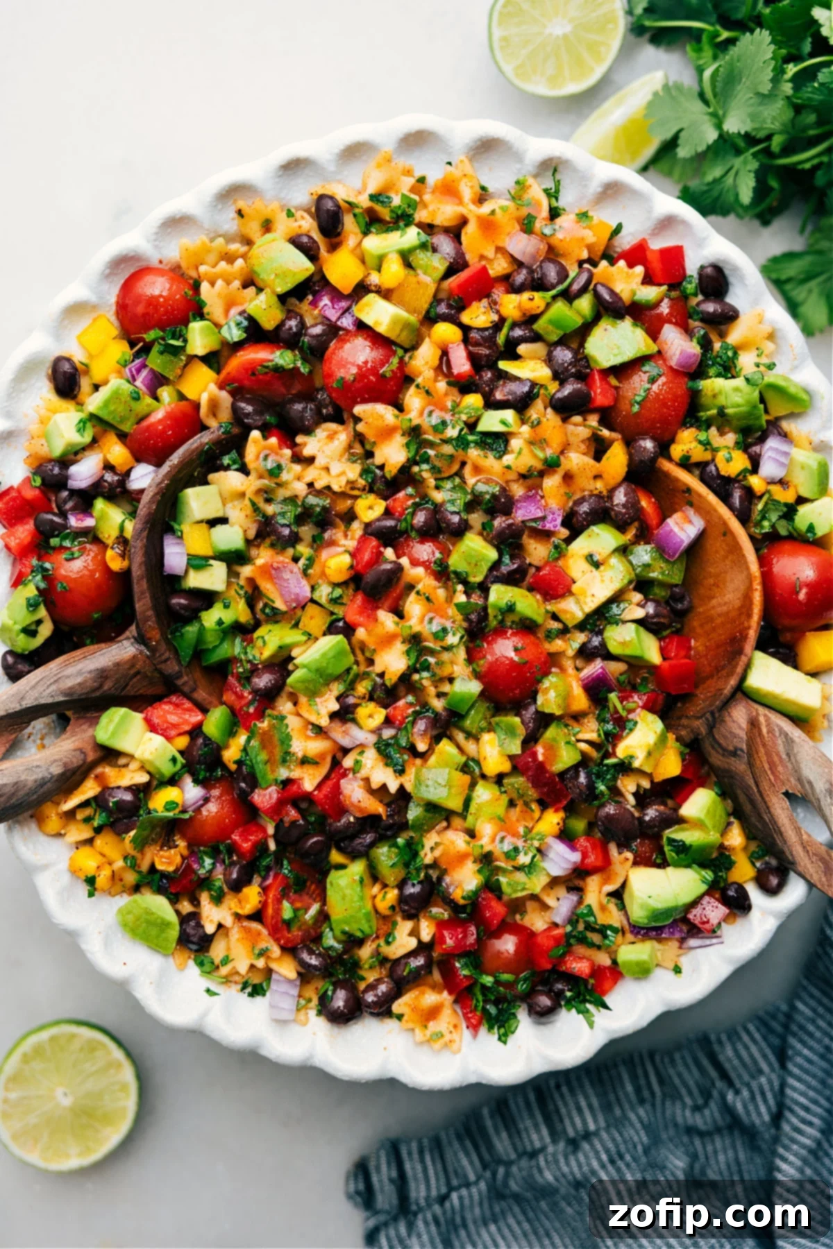 A large bowl of Mexican Pasta Salad, fully dressed and garnished with fresh cilantro, ready to be served and enjoyed at a vibrant outdoor gathering.