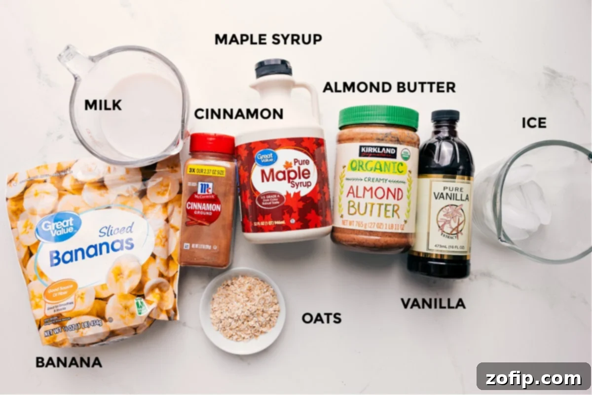 All the vibrant and fresh ingredients for the oatmeal smoothie meticulously prepped, including ripe bananas, almond milk, rolled oats, ground cinnamon, pure maple syrup, creamy almond butter, a hint of vanilla, and ice cubes.