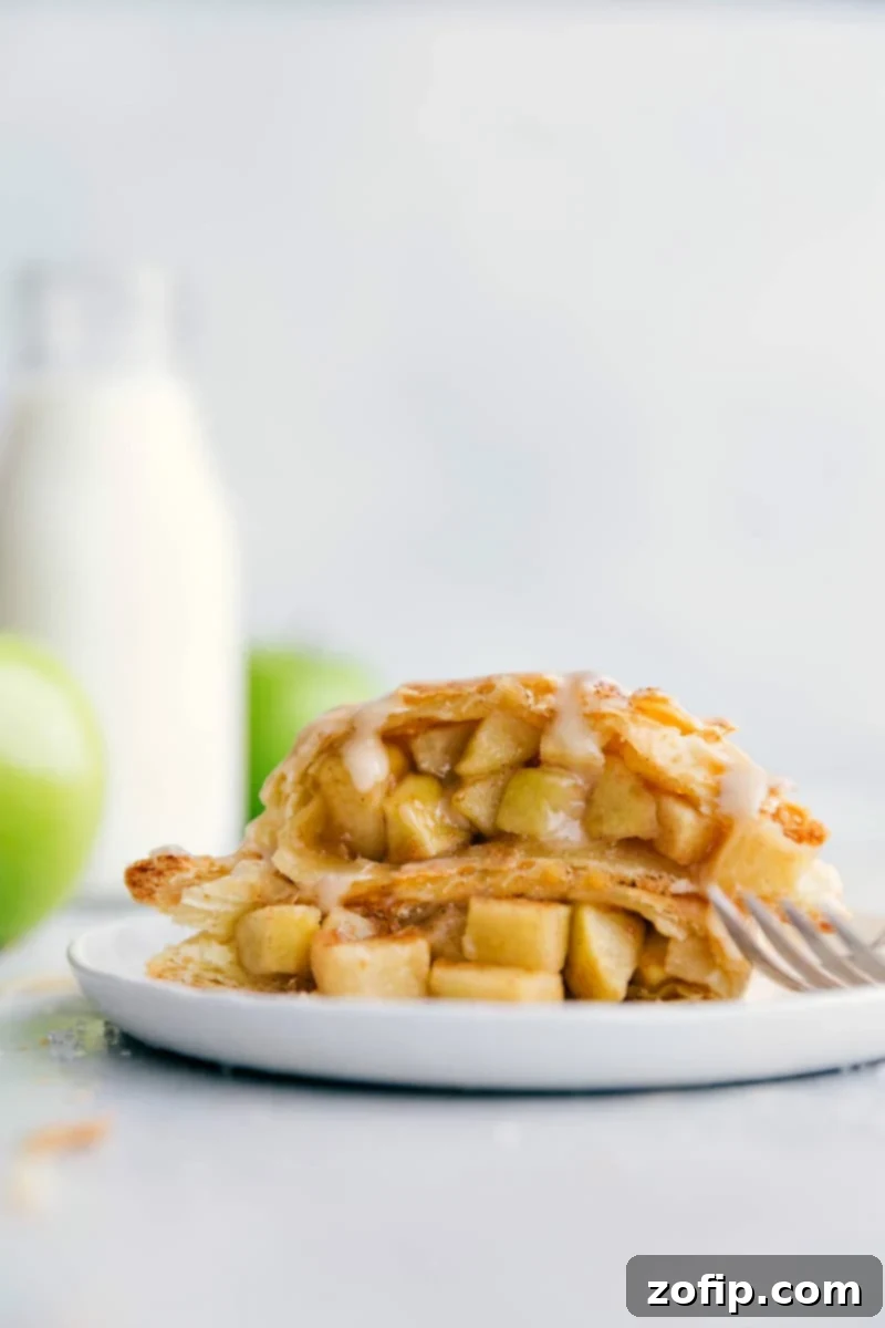 Two halves of a golden, flaky apple turnover stacked, showcasing its delicate layers and rich apple filling.