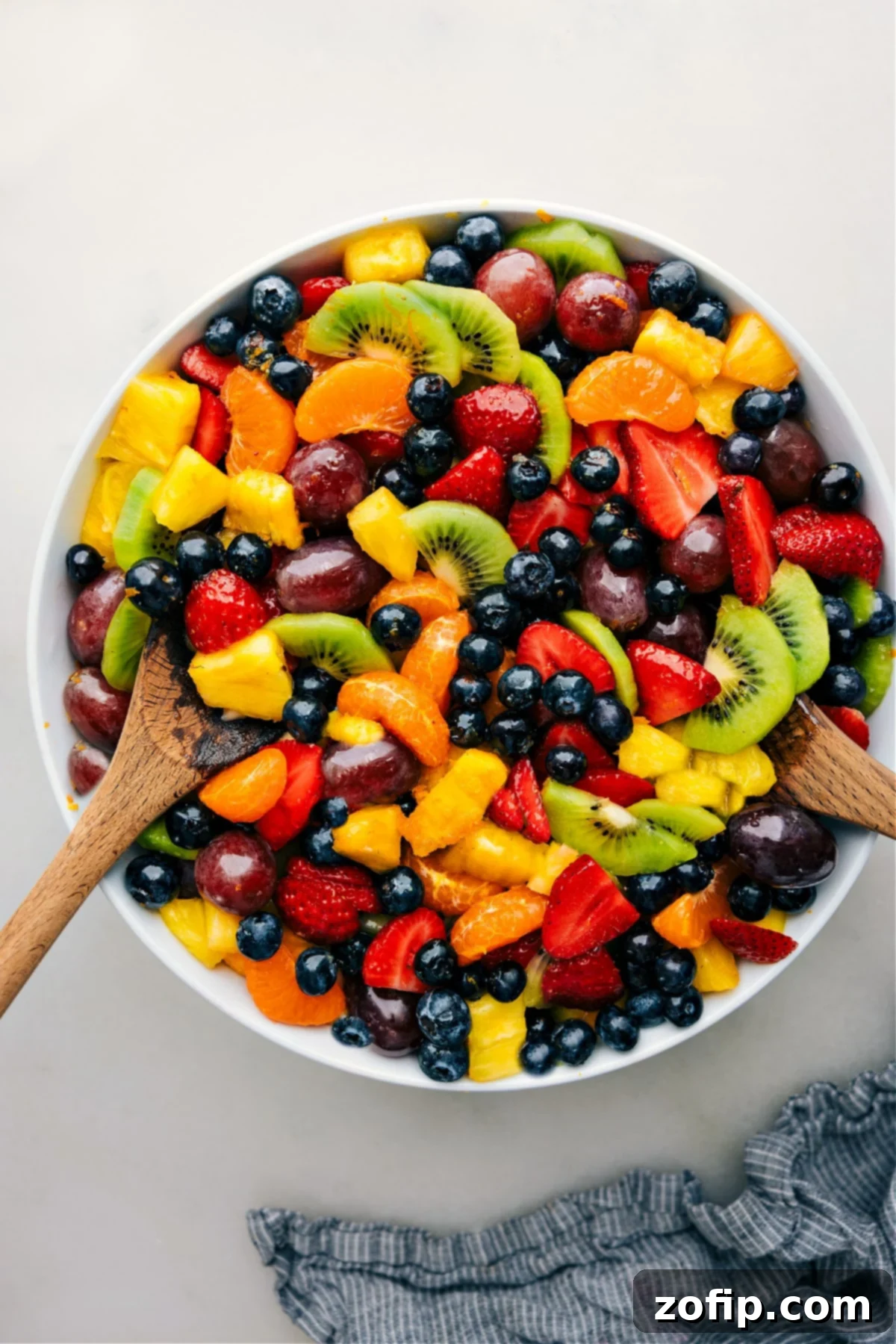 The Best Fruit Salad with Citrus Dressing A large bowl of the easy fruit salad recipe, vibrant and colorful, with serving spoons ready.