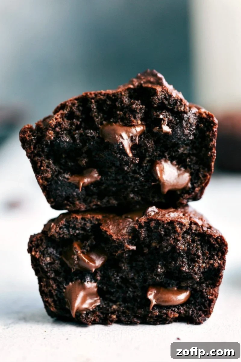 Chocolate peanut butter muffins, cut in half and stacked, revealing their soft interior with gooey chocolate chips.