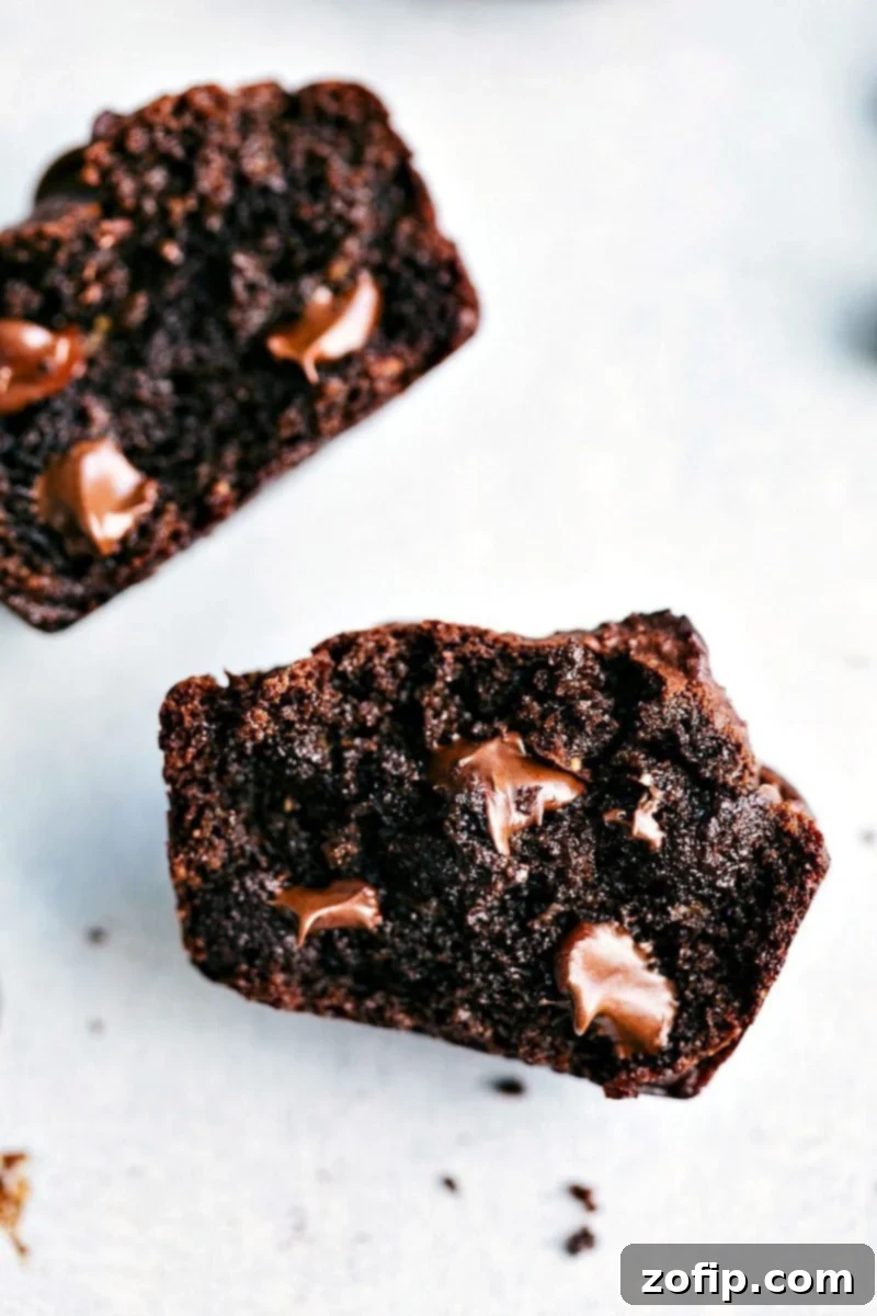 Halved peanut butter chocolate chip muffins with melted chocolate chips on the inside, showcasing their deliciousness.