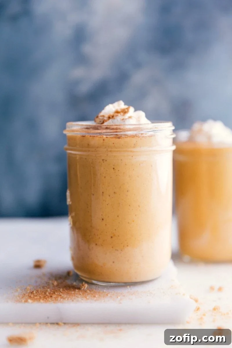 A cup filled with a creamy pumpkin protein shake, topped with a swirl of whipped cream.