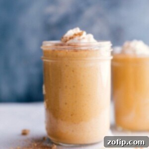 A cup filled with a creamy pumpkin protein shake, topped with a swirl of whipped cream.