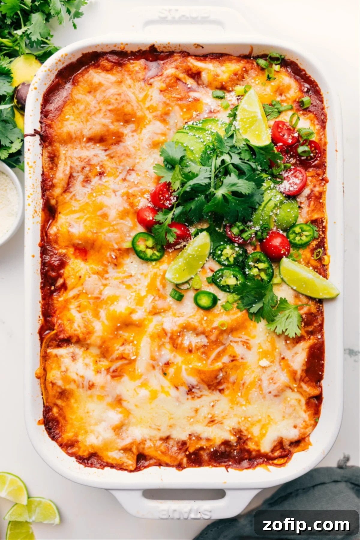 Freshly baked Chicken Enchilada Casserole, straight out of the oven, garnished with vibrant fresh cilantro, creamy diced avocado, juicy chopped tomatoes, and bright lime wedges.