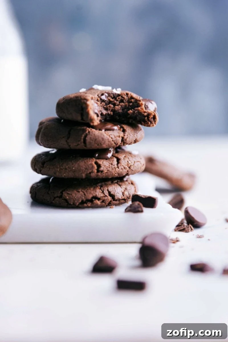 Stack of four healthy chocolate cookies with a bite taken out of the top one, revealing a soft, chewy interior and melted chocolate chips.