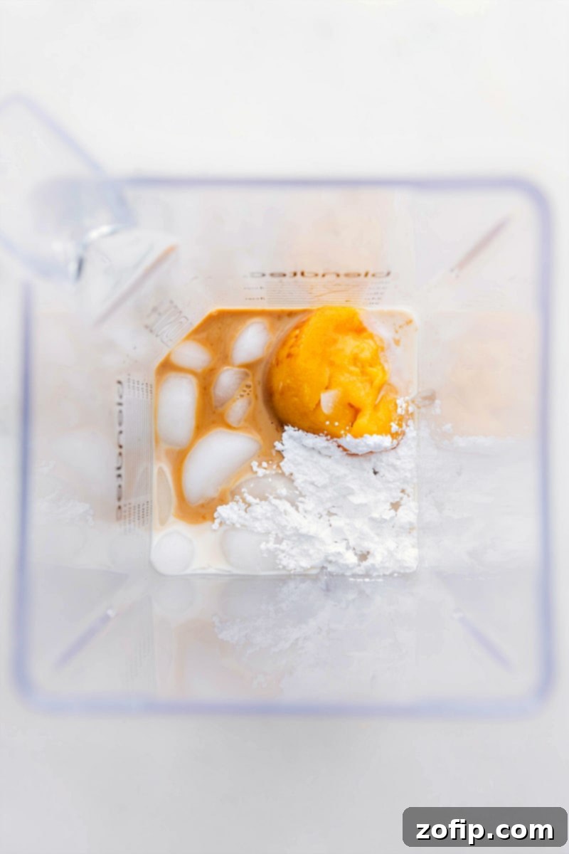 Ingredients for Orange Julius being added to a blender, showing frozen orange concentrate, milk, and sugar.