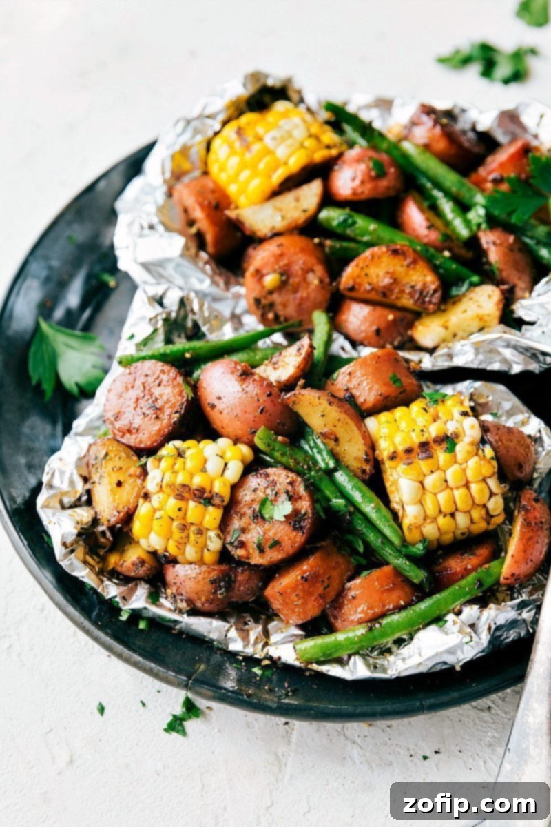 A close-up of a perfectly cooked garlic butter sausage and veggie foil pack, garnished with fresh parsley.