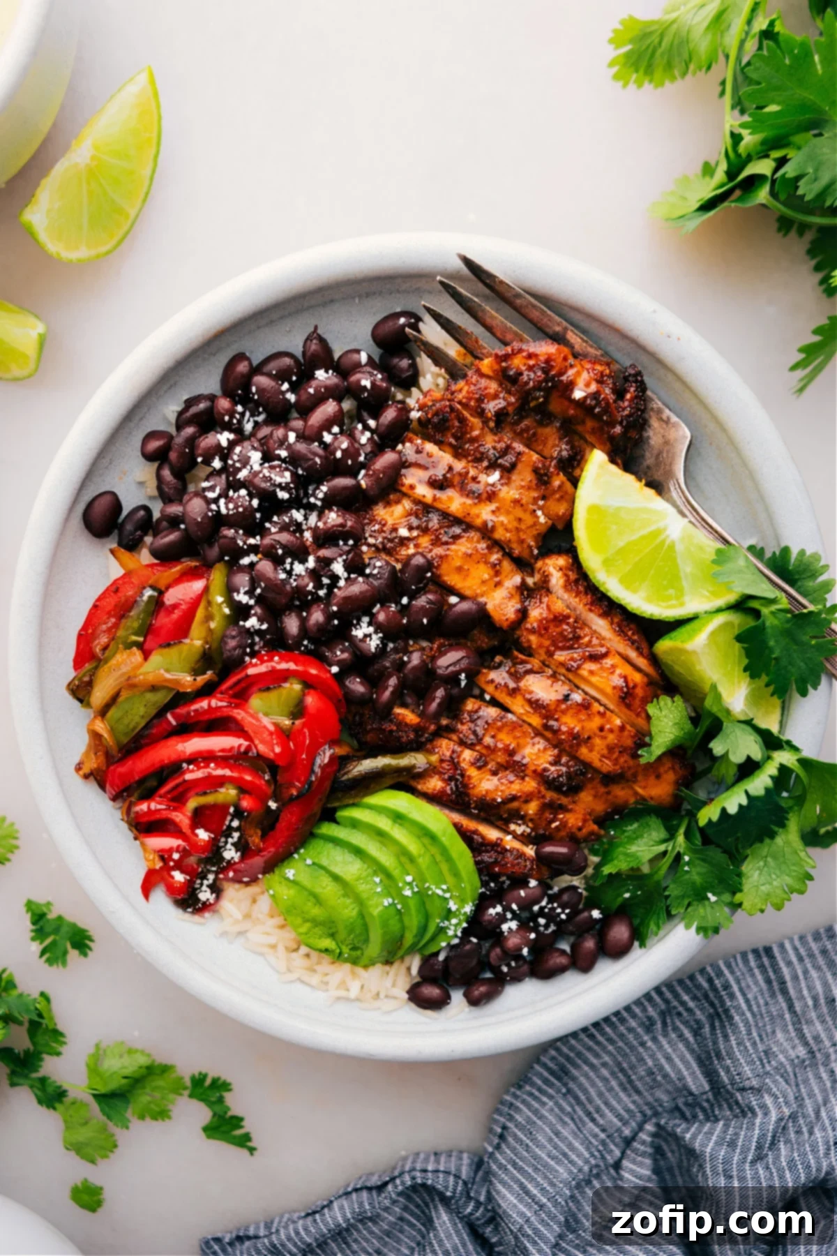 A vibrant and fully loaded Chicken Fajita Bowl, featuring juicy chicken, colorful peppers, onions, rice, and fresh toppings like avocado and cilantro, ready to be enjoyed.