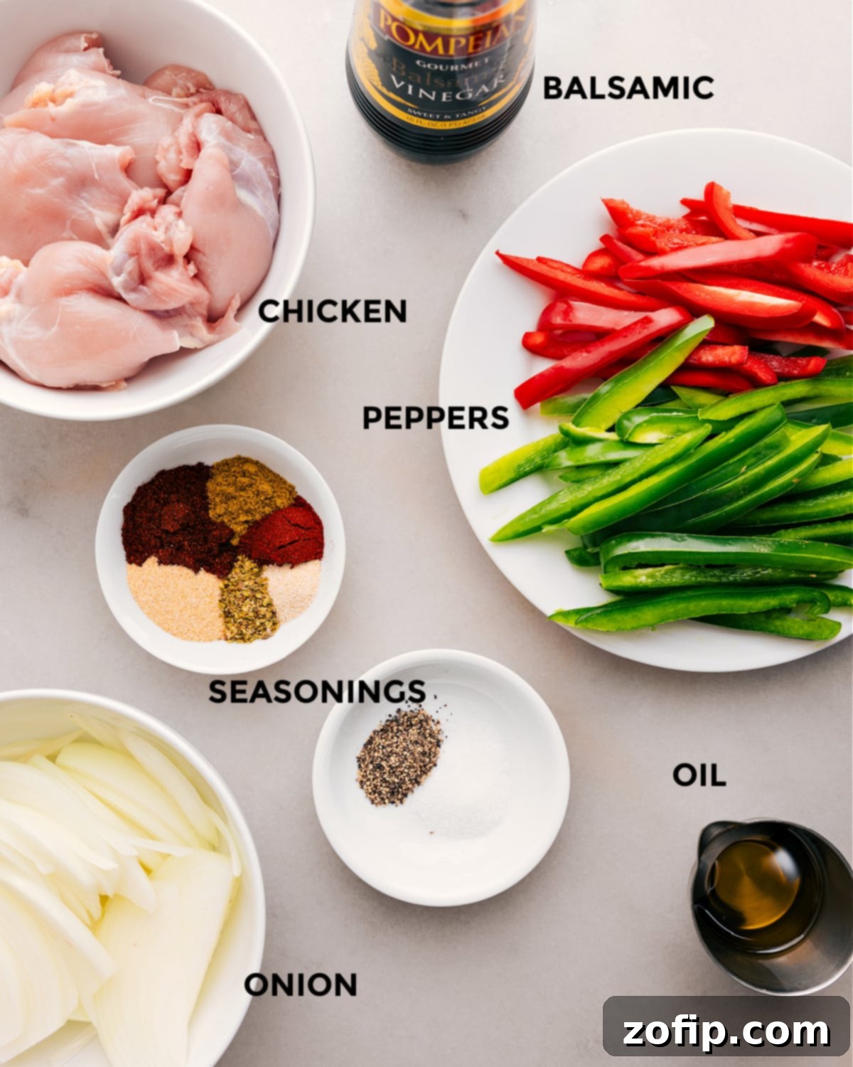 A comprehensive layout of all the fresh ingredients needed for this recipe, including seasoned chicken, thinly sliced bell peppers and onions, a variety of spices, balsamic vinegar, and olive oil.