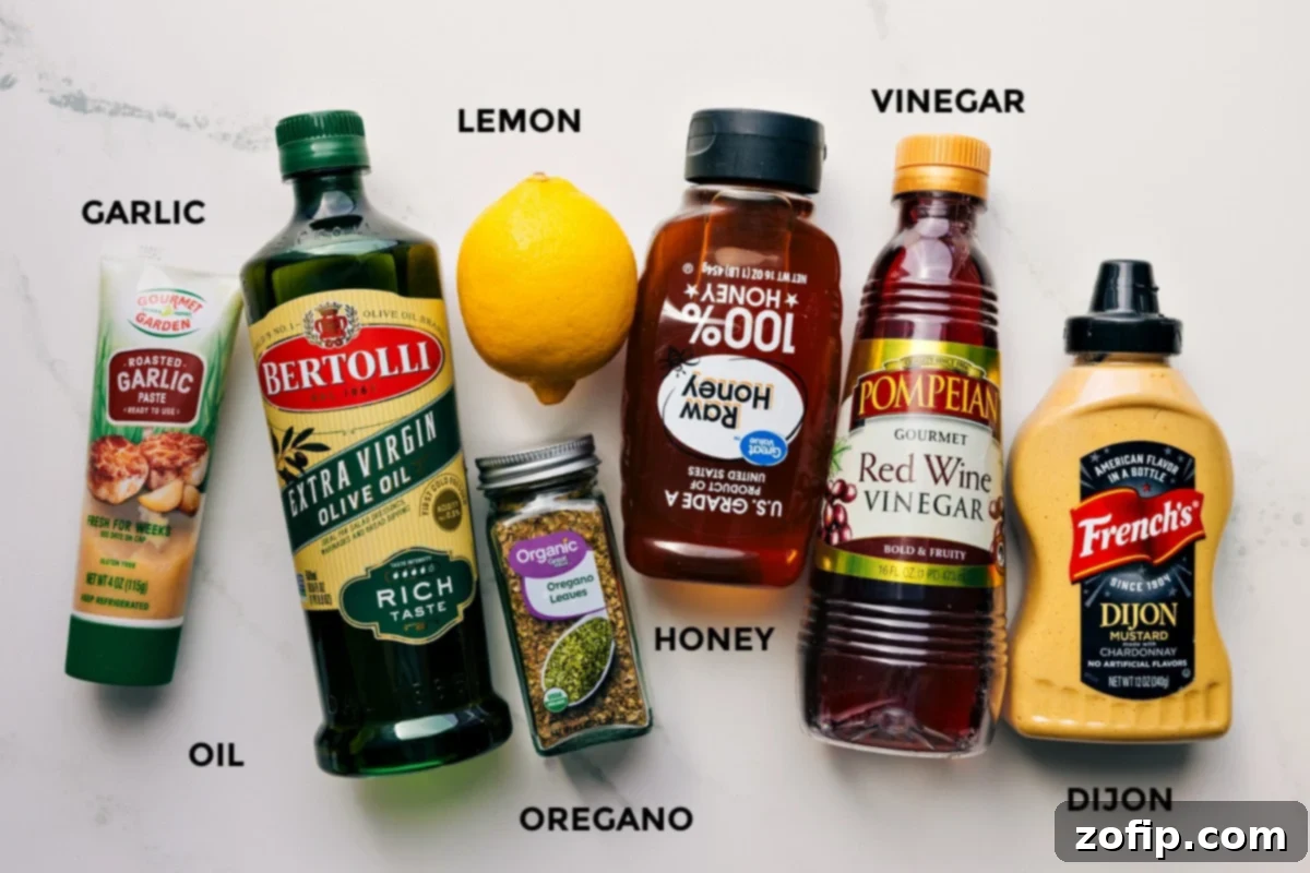 Essential ingredients for the vibrant lemon-oregano dressing, including fresh garlic, olive oil, juicy lemons, dried oregano, a touch of honey, red wine vinegar, and Dijon mustard, neatly arranged.
