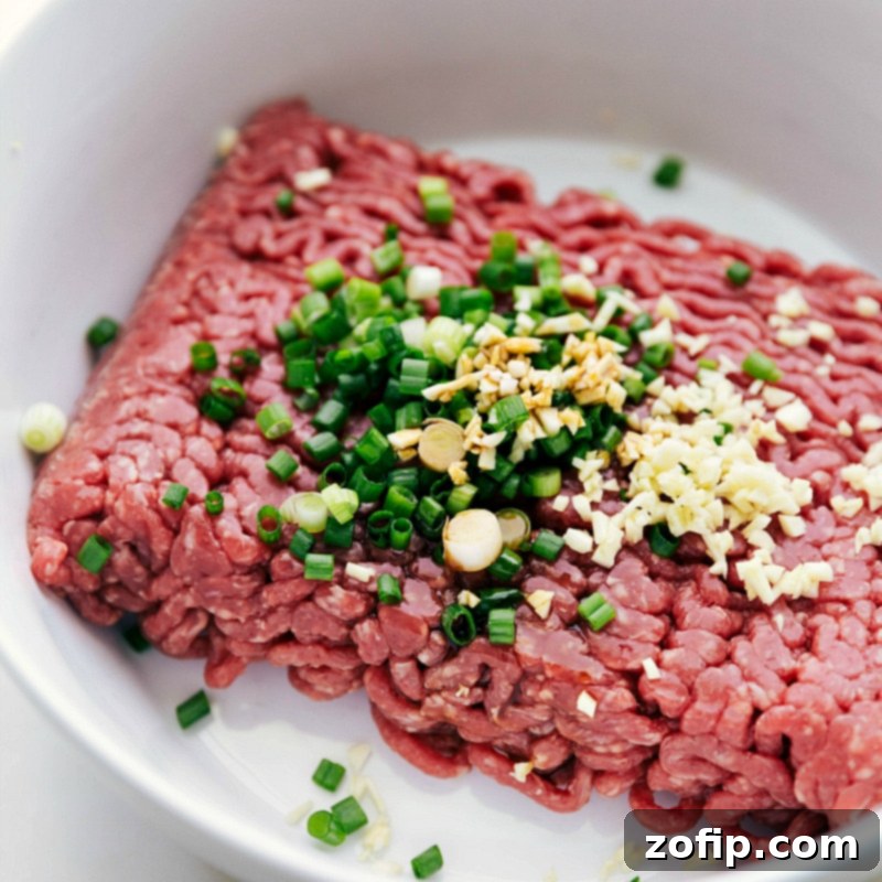 Combining ground beef with diced green onions and a blend of seasonings, capturing the initial step in preparing the best burger recipe, ensuring even flavor distribution.