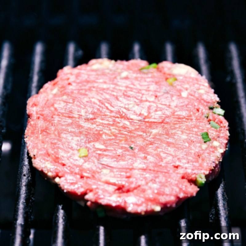 A beef patty sizzling on the grill, being cooked to perfection over high heat, ensuring a juicy and flavorful patty with a beautiful sear.
