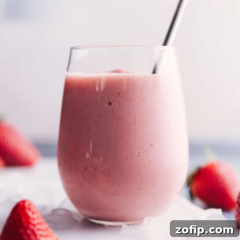 You'll love the flavors in this Jamba Juice copycat smoothie recipe! Recipe via ChelseasMessyApron #breakfast #quick #easy #simple #best #healthy #dessert #ice #jambajuice #strawberry #wild #smoothie Close-up of Jamba Juice Strawberry Wild copycat smoothie in a glass with a fresh strawberry garnish