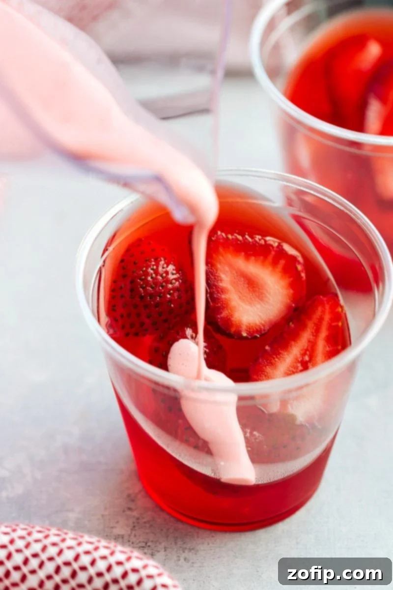 The coolest and EASIEST hack to make these slanted jell-o parfait cups with a strawberry mousse on top. Delicious and so easy! Recipe from chelseasmessyapron.com