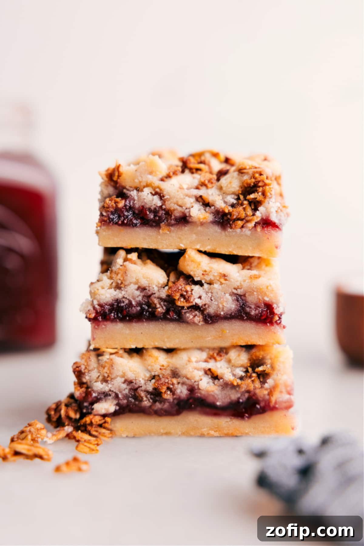 Stacked Raspberry Bars showing off the yummy layers of shortbread, raspberry jam, and crunchy topping.