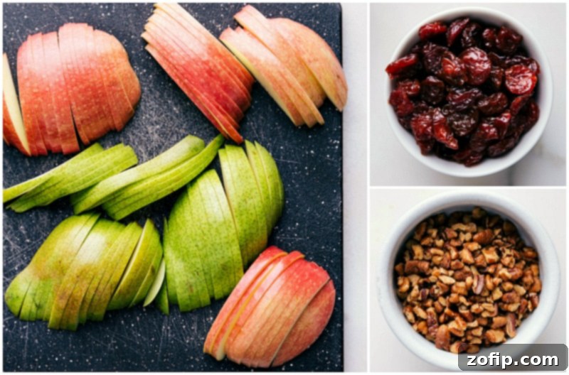 Fresh apple, pear, dried cranberries, and walnuts, key ingredients for the apple salad recipe, arranged beautifully.