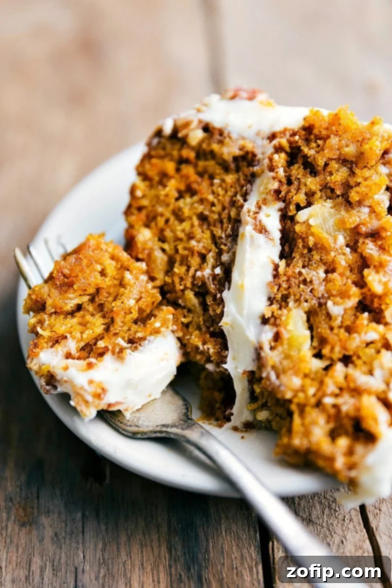 A close-up of a delightful slice of Pumpkin Carrot Cake, with a bite taken out, showcasing its rich, spiced flavor, moist texture, and the creamy white icing on top.