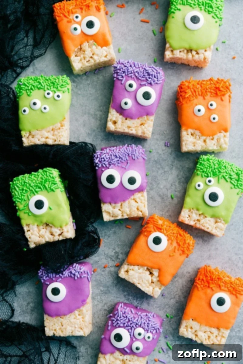 A close-up of vibrant Monster Rice Krispies Treats with various candy eyeballs and colorful sprinkles, ready for Halloween festivities.