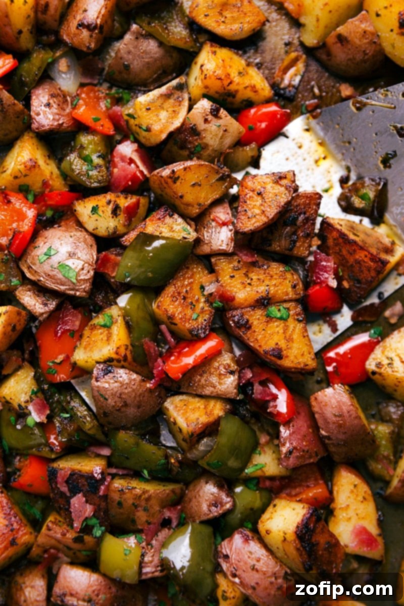 Sheet Pan Bacon Potato Roast 2 Close-up of golden brown oven-roasted breakfast potatoes and crispy bacon with colorful bell peppers and onions on a sheet pan.