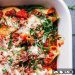 A pan of stuffed shells with sausage, topped with melted cheese and a basil chiffonade, presenting a warm and delicious meal suitable for any occasion.