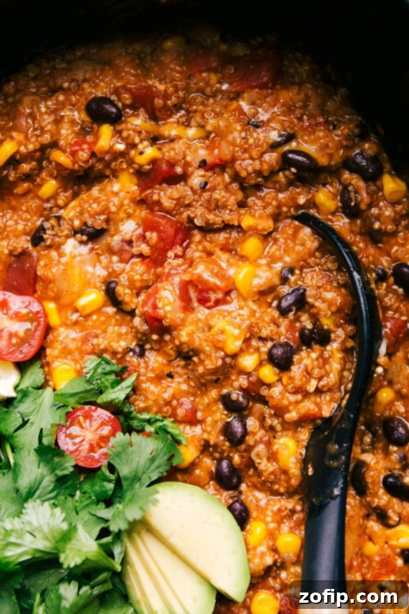 Hearty Enchilada Quinoa Crockpot Meal Ready to Enjoy The finished enchilada quinoa dish presented within a slow cooker, looking rich and flavorful, with a serving spoon nestled inside, signifying it's perfectly cooked and ready for serving.