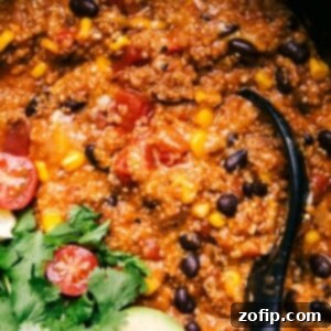 Easy Slow Cooker Quinoa Enchiladas 2 Finished enchilada quinoa dish in a crockpot, rich and flavorful, with a spoon nestled inside, ready for serving.