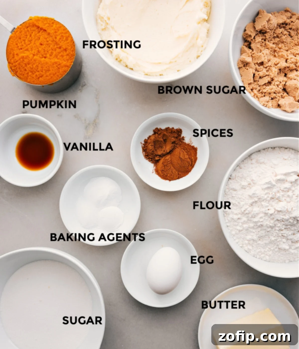 Recipe ingredients for pumpkin cookies with cream cheese frosting laid out: sugar, spices, flour, baking agents, egg, butter, vanilla, and pumpkin.