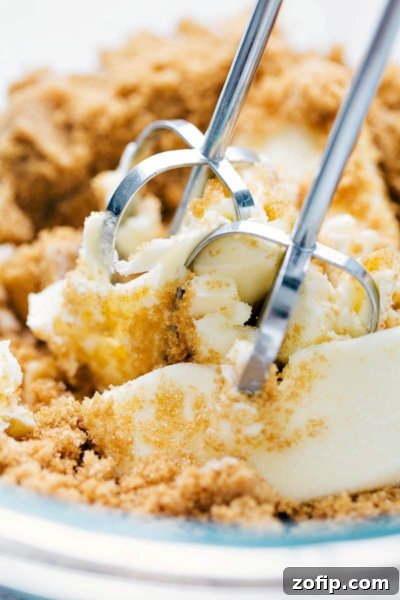 Butter and sugar being vigorously beaten together in a bowl until smooth and creamy, a key step in preparing the pumpkin cupcake batter.