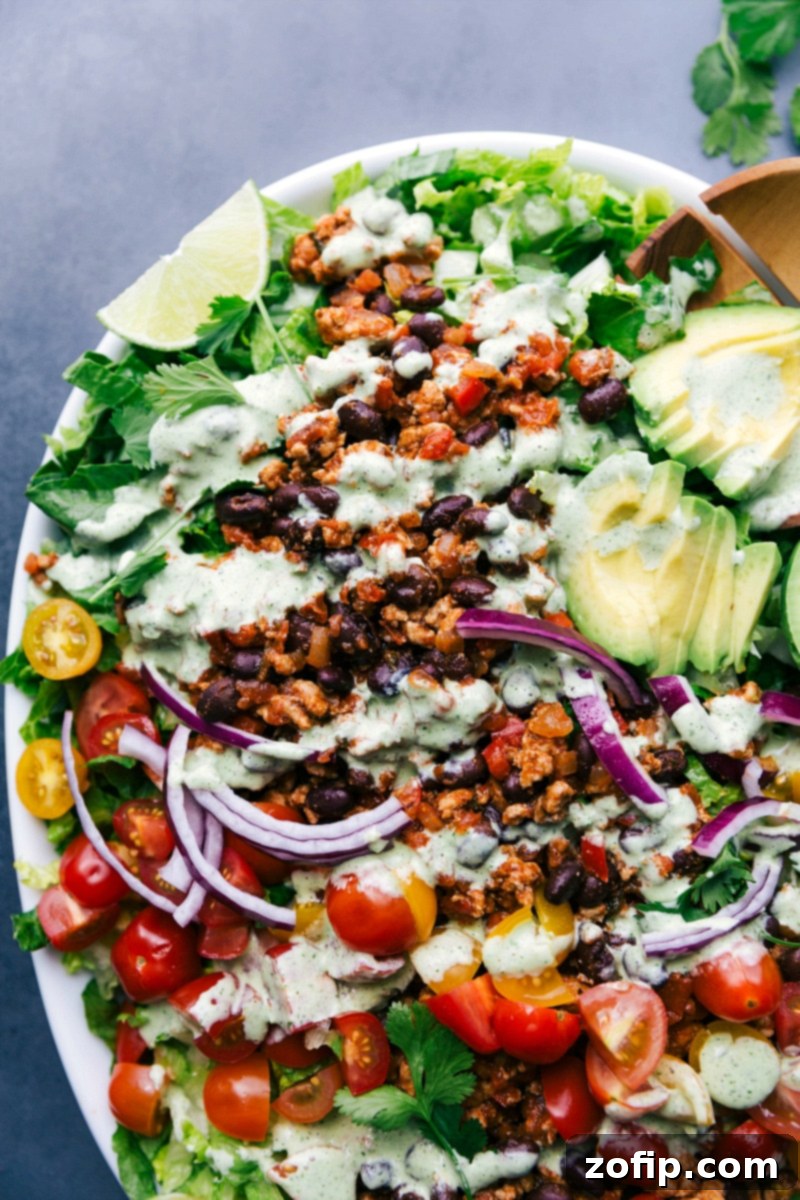 A vibrant and colorful Turkey Taco Salad, richly dressed with creamy cilantro dressing and piled high with fresh toppings like avocado, tomatoes, and cheese, ready to be served and enjoyed.