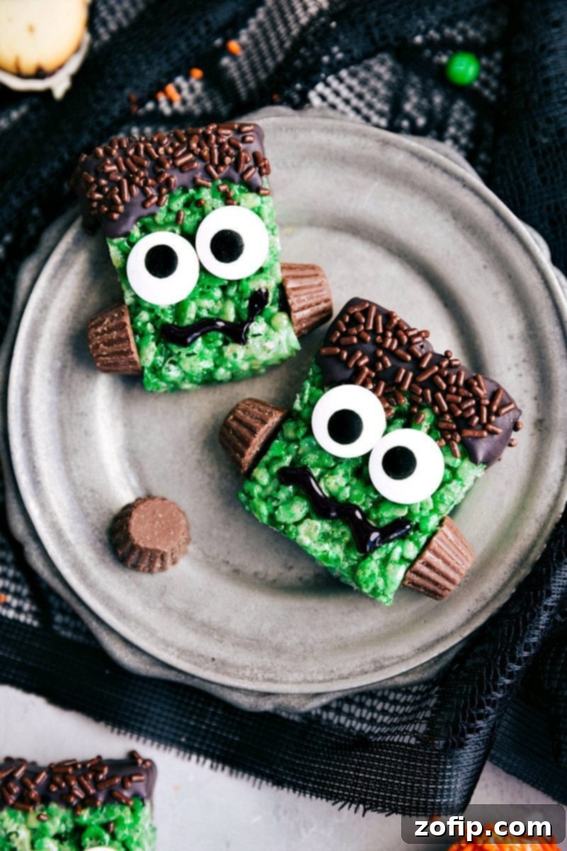 Frankenstein Rice Krispies Treats - Halloween Party Food Image of two Frankenstein Rice Krispies Treats, green with candy eyes and chocolate hair.