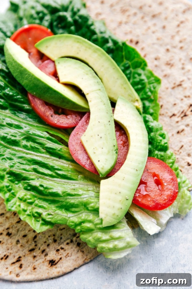 Our absolute favorite chicken salad Whole wheat tortilla layered with fresh romaine lettuce, sliced tomatoes, and avocado, ready for chicken salad filling.