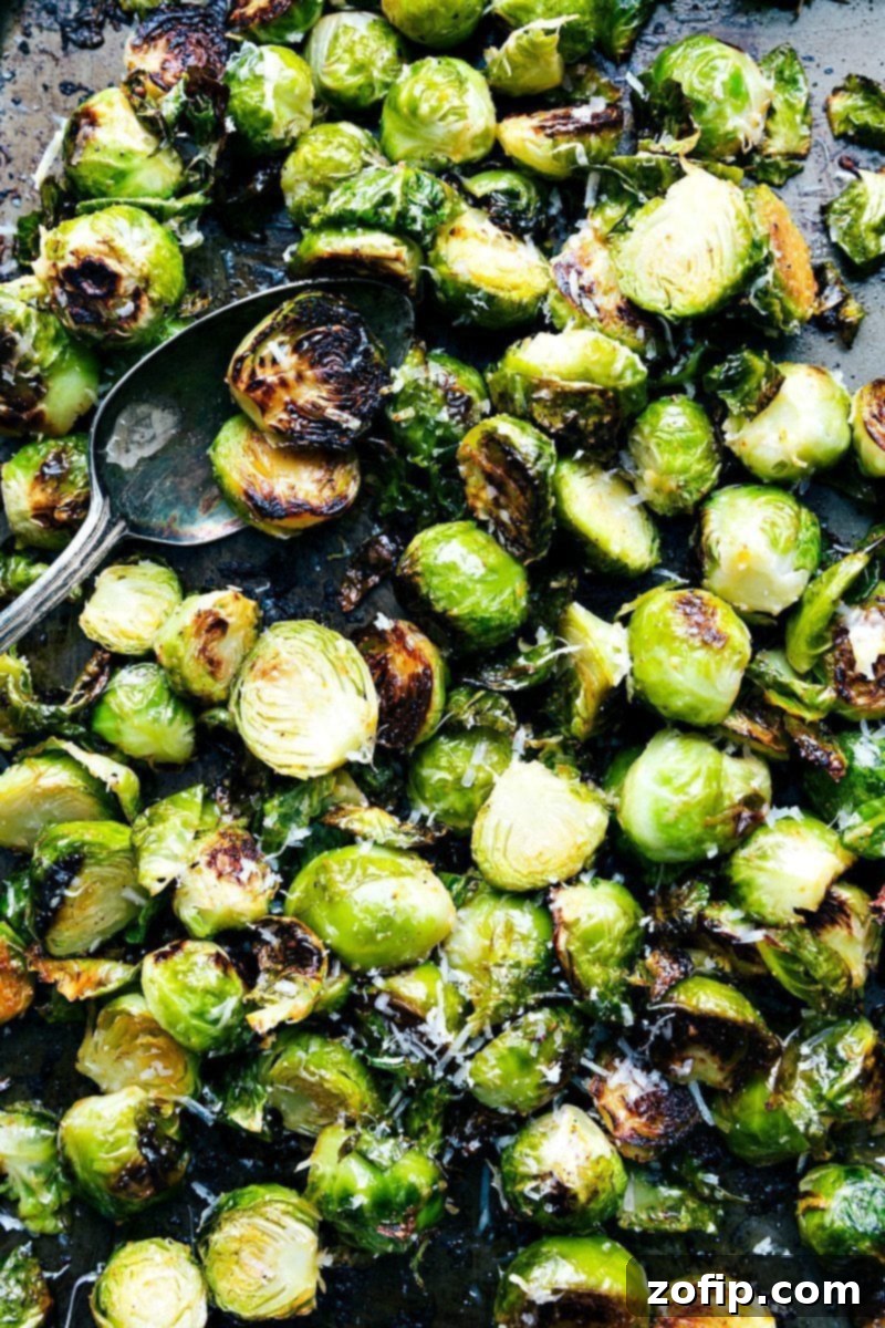 Crispy roasted Brussels sprouts tossed with seasoning, laid out on a sheet pan, representing a healthy and delicious Thanksgiving dinner side.