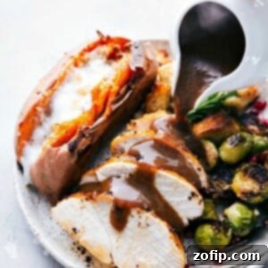 A Thanksgiving dinner plate, beautifully plated with turkey, gravy, dressing, sweet potatoes, and Brussels sprouts, prepared efficiently on two sheet pans, ready to be enjoyed.