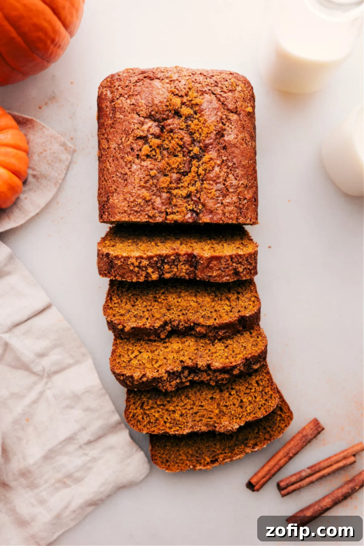 A beautifully baked loaf of moist pumpkin bread, half-sliced to reveal its tender interior, ready to be enjoyed with a cup of coffee.