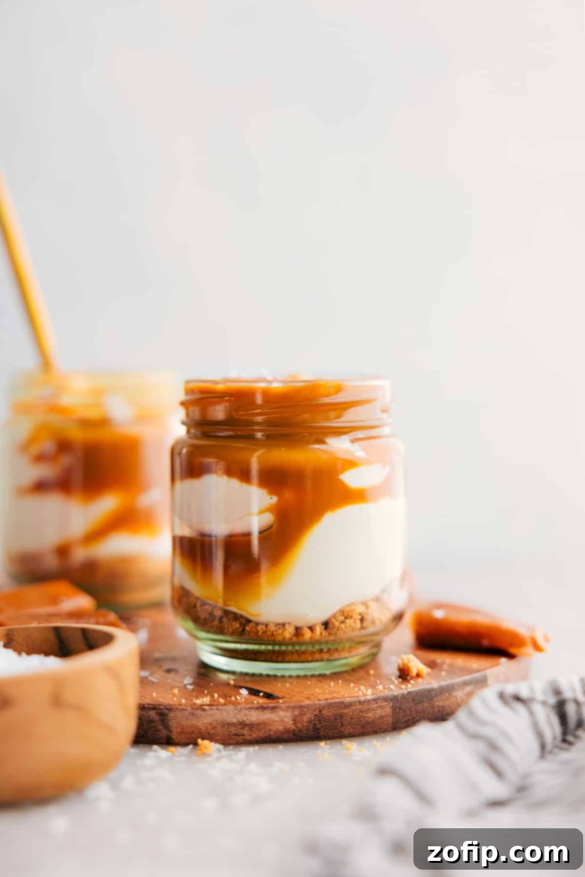 A vibrant close-up of a cheesecake in a jar topped with an abundance of fresh raspberries and a sprig of mint.