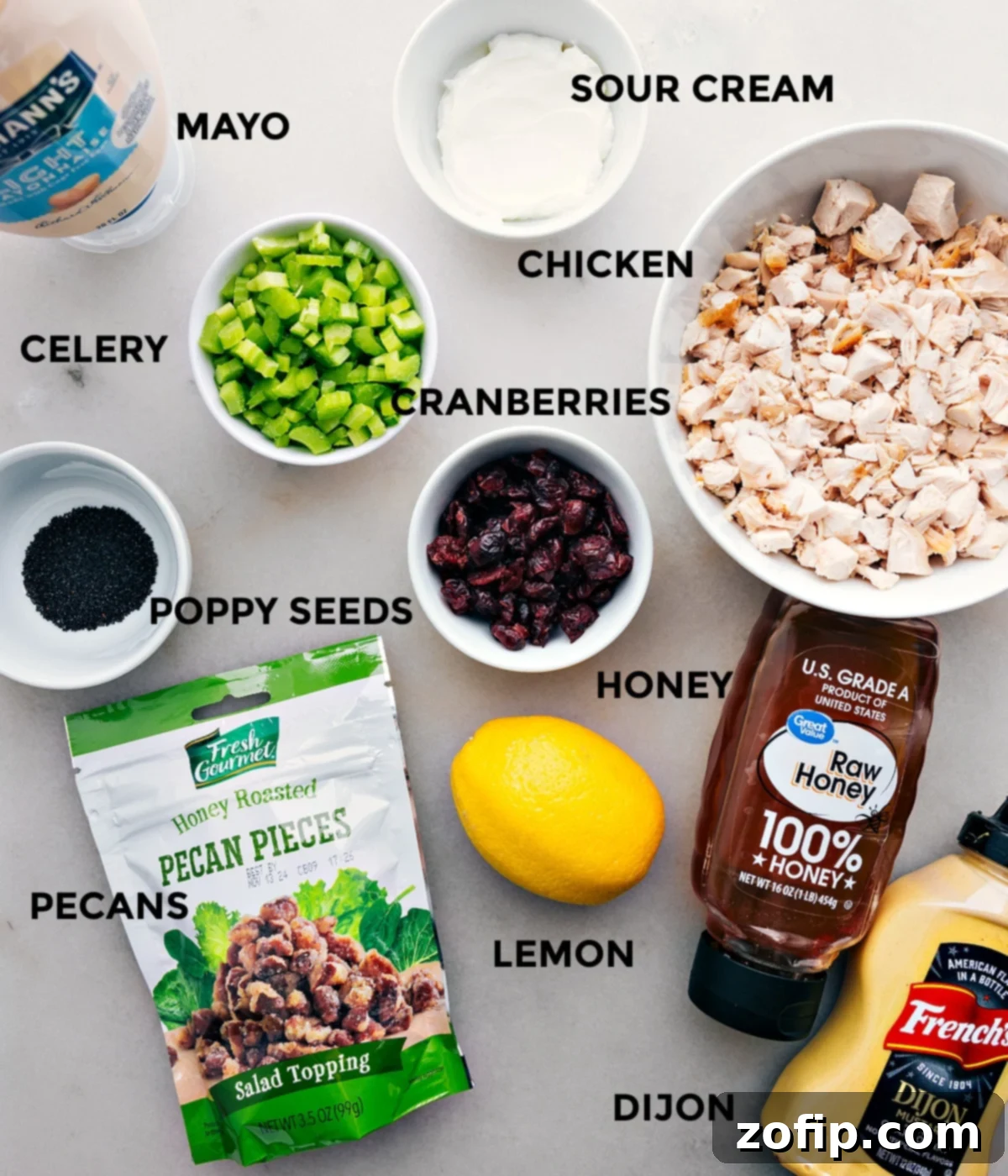 All the fresh ingredients for this chicken salad recipe, including shredded chicken, creamy dressing components, crisp celery, vibrant cranberries, and crunchy pecans, neatly prepped for easy assembly.