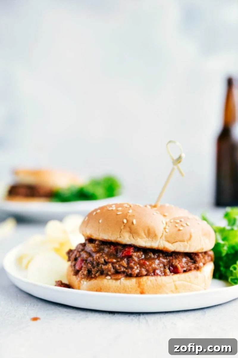 A perfectly assembled Crockpot Sloppy Joe sandwich on a plate, showcasing the rich, savory filling spilling slightly from a toasted brioche bun, ready to be enjoyed.