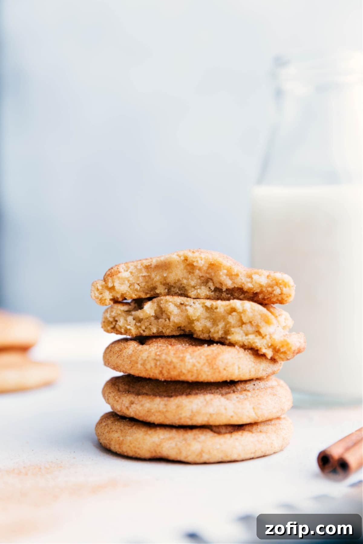 Freshly Baked Snickerdoodle Cookies on a Plate Stack of freshly baked snickerdoodle cookies on a plate, with one broken in half to reveal the soft and delicious interior.