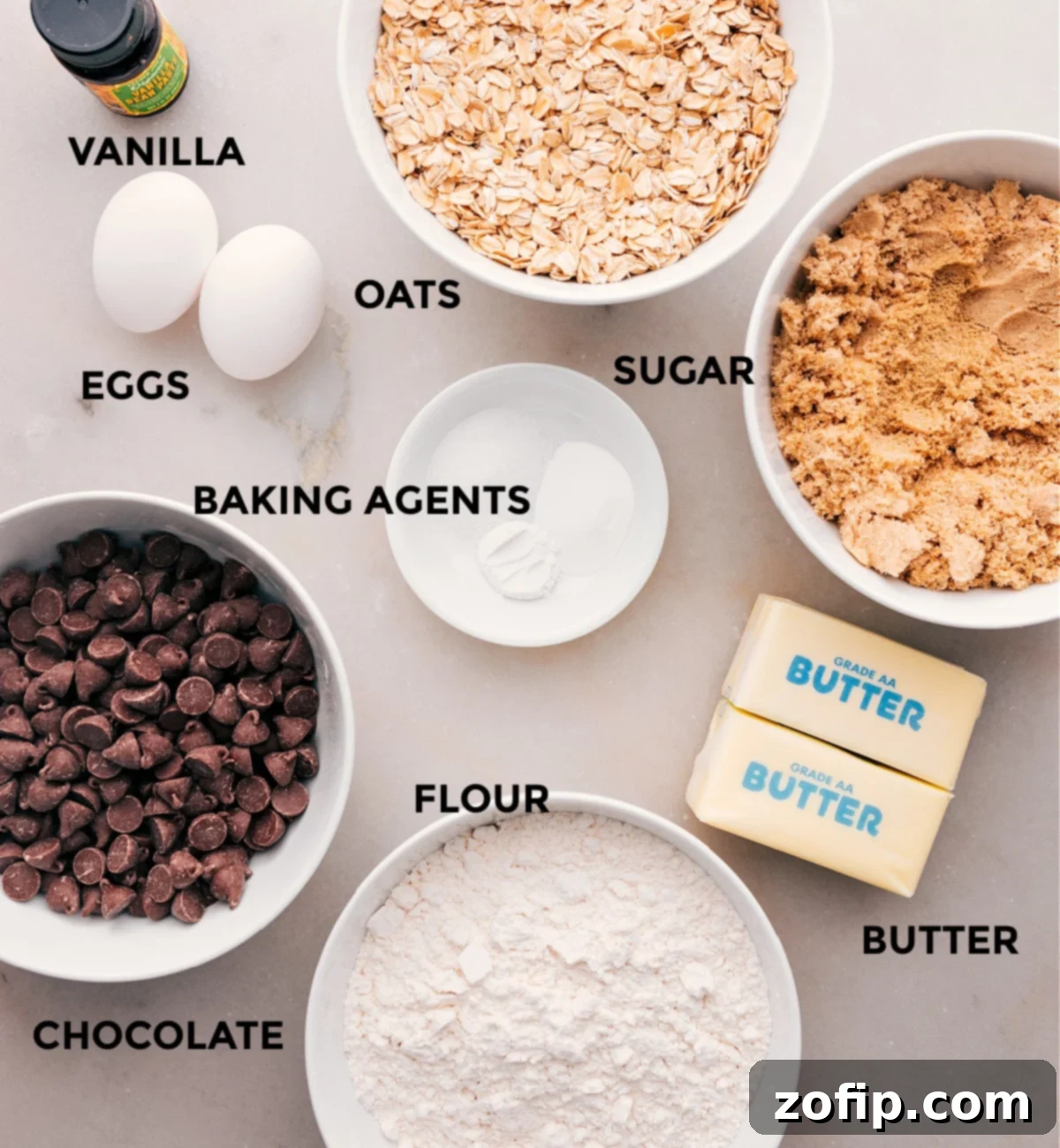 All the essential ingredients for delicious Brown Butter Oatmeal Chocolate Chip Cookies, including flour, chocolate, butter, sugar, oats, vanilla, eggs, and baking agents, neatly prepped and ready for baking.