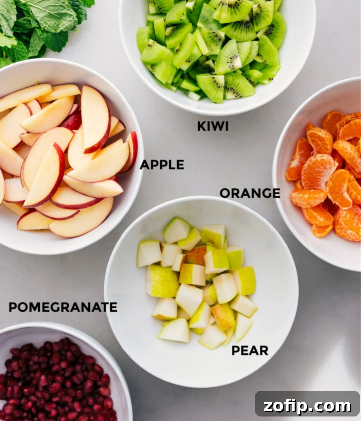 All the fresh ingredients for this delicious Winter Fruit Salad are neatly prepped and ready for assembly: brightly colored kiwis, crisp apples, juicy oranges, tender pears, and gleaming pomegranates.